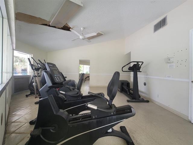 workout room featuring ceiling fan, lofted ceiling, and a textured ceiling