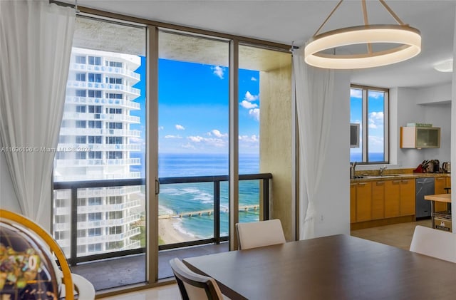 dining space featuring expansive windows, a water view, a beach view, and sink