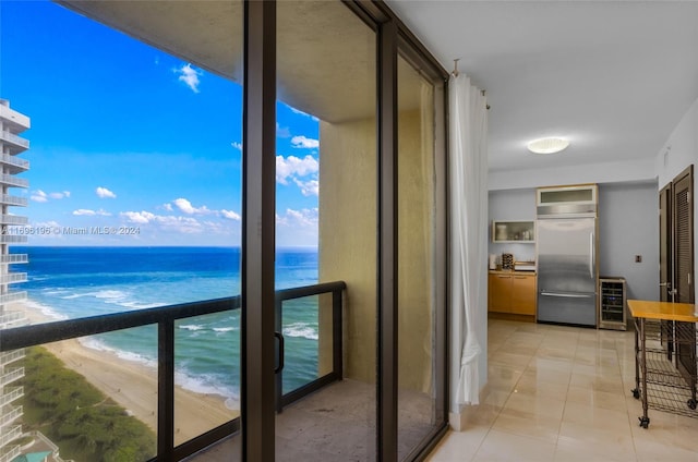 balcony with wine cooler, a water view, and a view of the beach