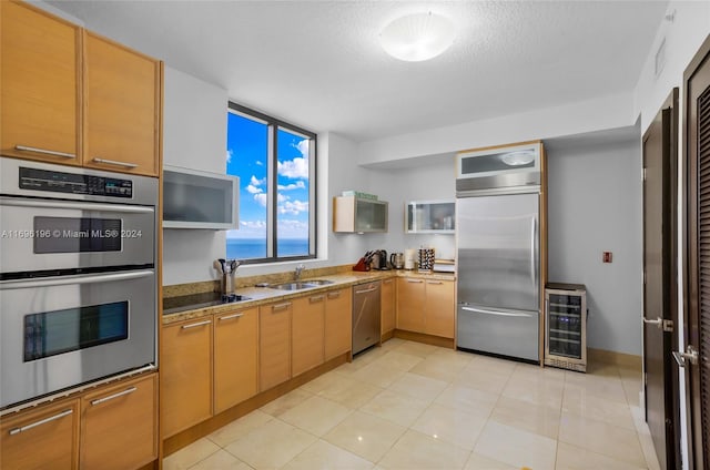 kitchen with a textured ceiling, stainless steel appliances, beverage cooler, a water view, and stone counters