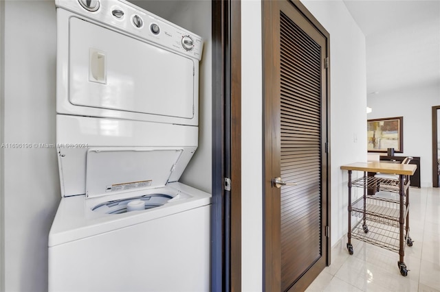 clothes washing area with light tile patterned floors and stacked washer and dryer