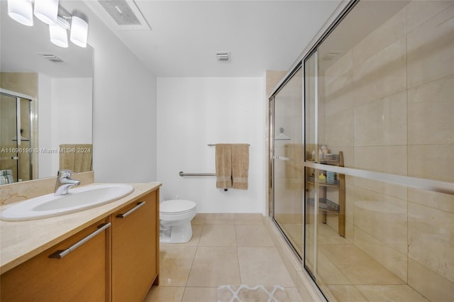 bathroom with tile patterned flooring, vanity, toilet, and a shower with shower door