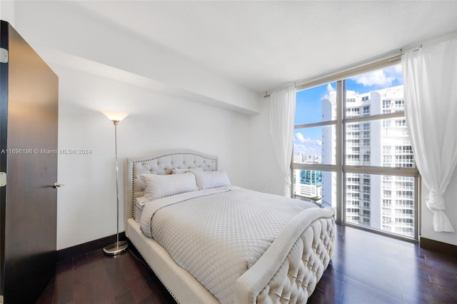 bedroom featuring multiple windows, dark hardwood / wood-style floors, and a wall of windows