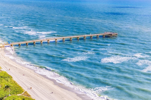 view of dock with a water view and a beach view