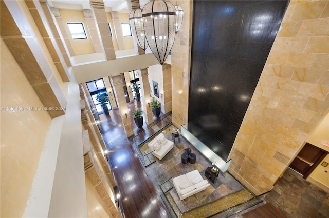 living room featuring plenty of natural light, a towering ceiling, tile walls, and an inviting chandelier