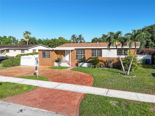 single story home featuring concrete driveway, a fenced front yard, a front yard, and stucco siding