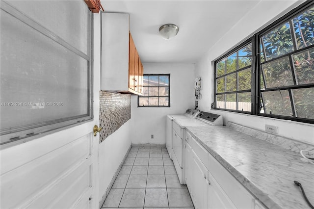 kitchen featuring washer and clothes dryer, white cabinetry, and light tile patterned floors