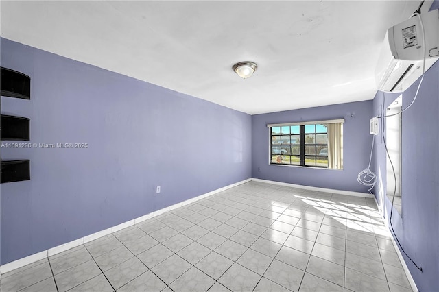 spare room featuring light tile patterned floors, baseboards, and a wall mounted air conditioner