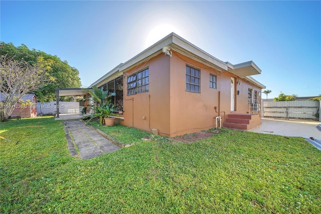 view of side of property with stucco siding, a yard, and fence