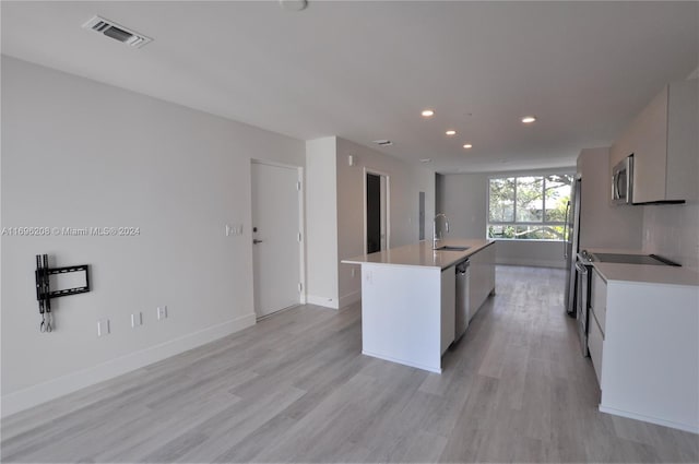 kitchen featuring white cabinetry, sink, a kitchen island with sink, appliances with stainless steel finishes, and light wood-type flooring