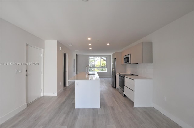 kitchen featuring backsplash, a center island with sink, sink, light hardwood / wood-style flooring, and appliances with stainless steel finishes