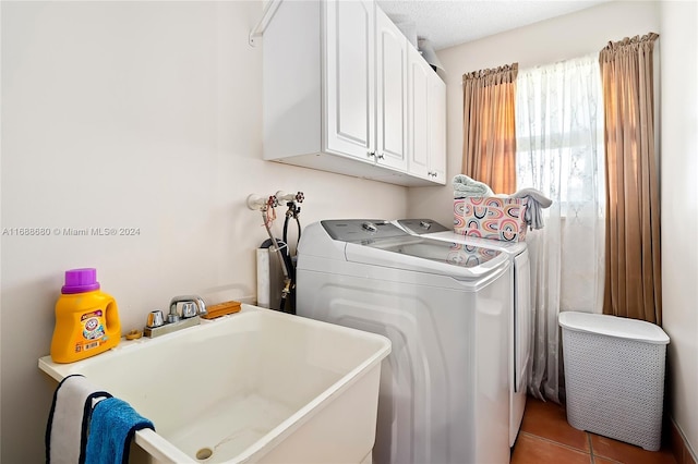 laundry room with cabinets, a textured ceiling, dark tile patterned floors, sink, and separate washer and dryer