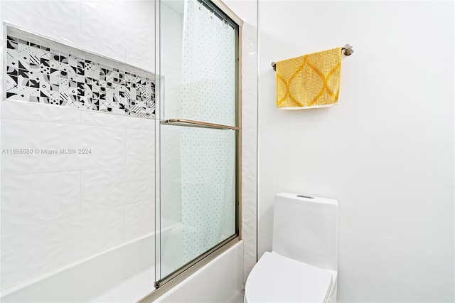 bathroom featuring toilet and combined bath / shower with glass door