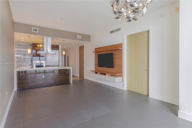 unfurnished living room with dark tile patterned floors and an inviting chandelier