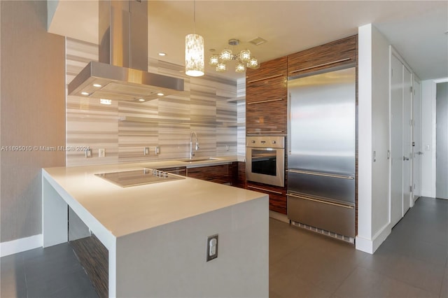 kitchen with sink, hanging light fixtures, appliances with stainless steel finishes, island range hood, and kitchen peninsula