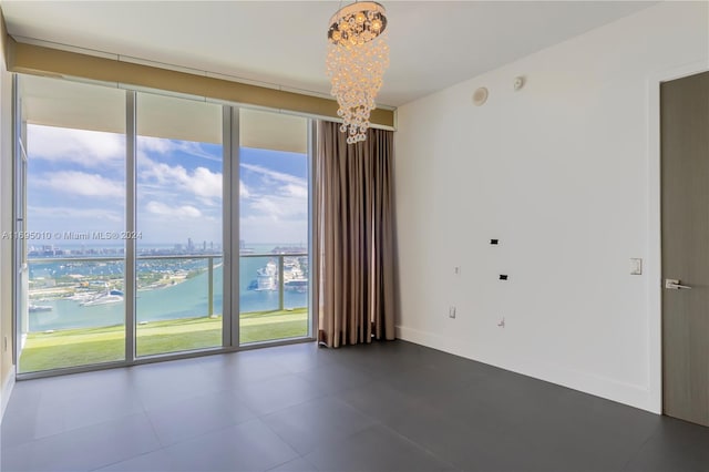 spare room featuring a water view and a chandelier