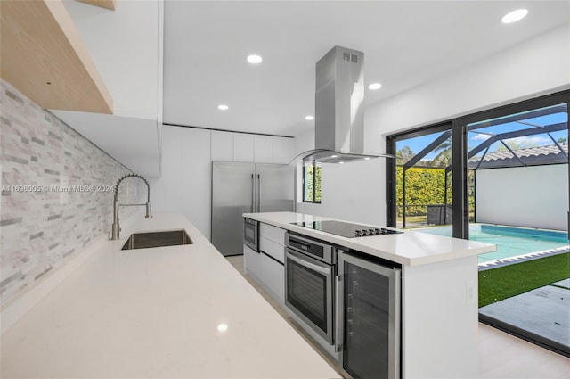 kitchen with white cabinetry, sink, wine cooler, built in appliances, and island range hood