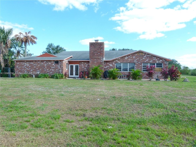 rear view of property featuring a lawn and french doors