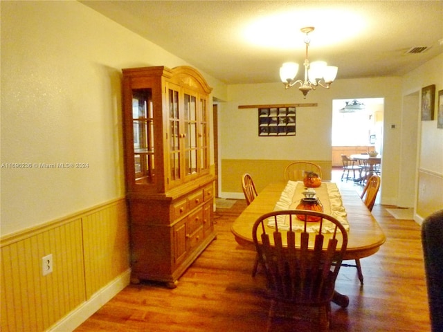 dining space featuring hardwood / wood-style flooring and an inviting chandelier