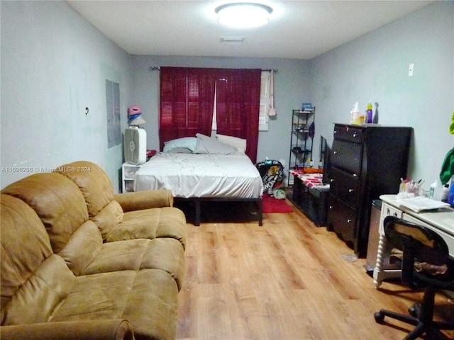 bedroom with electric panel and hardwood / wood-style flooring