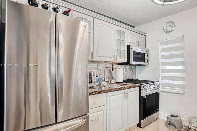1900 SW 21st Ave, Miami, FL 33145 - kitchen featuring appliances with stainless steel finishes, glass insert cabinets, tasteful backsplash, dark stone counters, and white cabinets