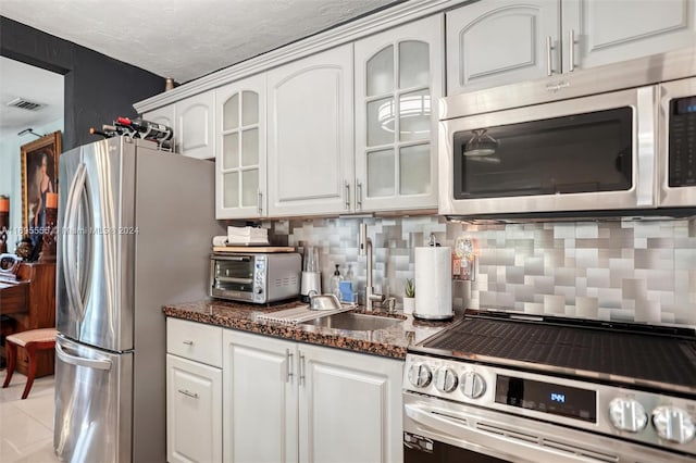 1900 SW 21st Ave, Miami, FL 33145 - kitchen with appliances with stainless steel finishes, white cabinets, tasteful backsplash, dark stone countertops, and glass insert cabinets