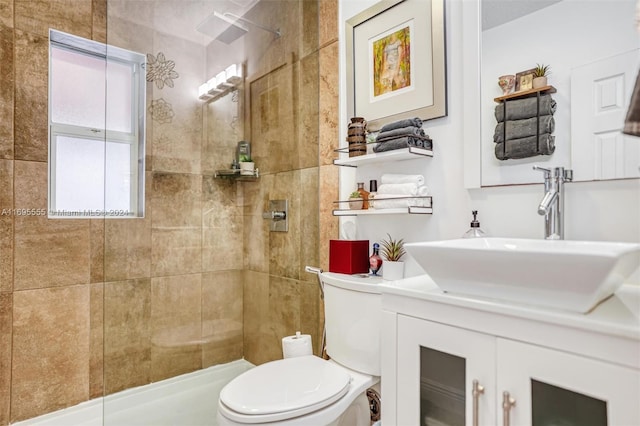 bathroom with a tile shower, vanity, and toilet