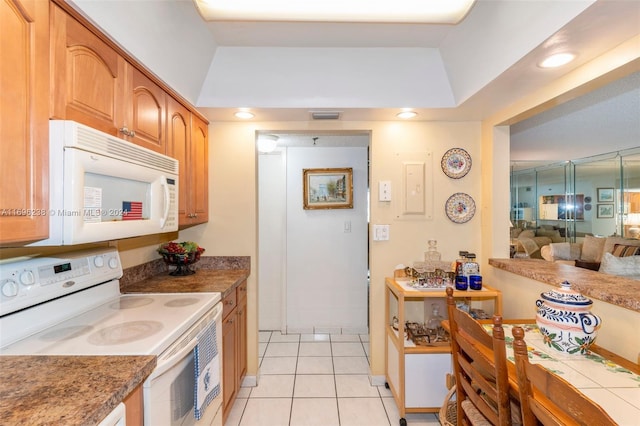 kitchen featuring light tile patterned flooring, white appliances, and a tray ceiling