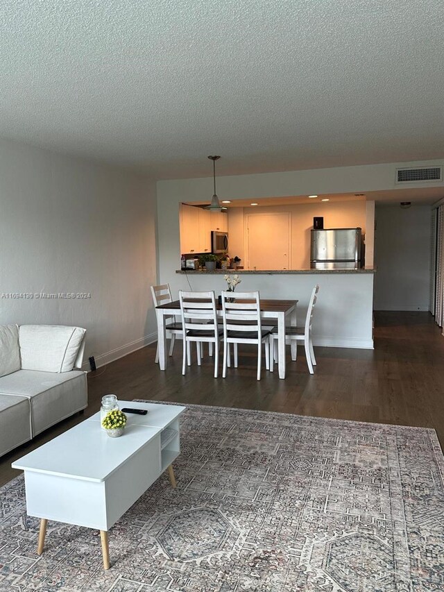 unfurnished living room with dark hardwood / wood-style flooring and a textured ceiling