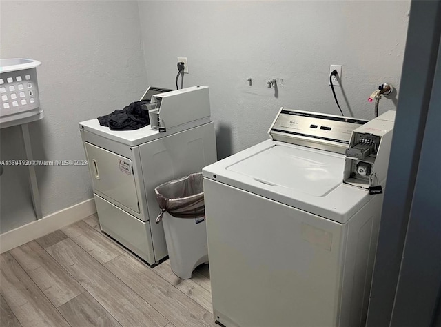 laundry area with washing machine and clothes dryer and light wood-type flooring