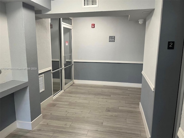 hallway with light hardwood / wood-style floors