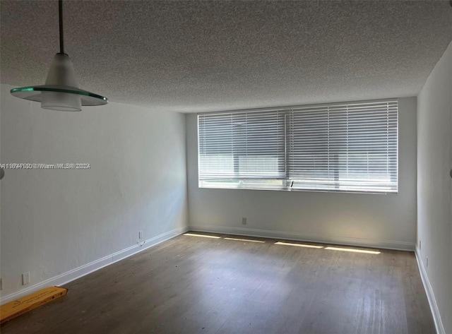 empty room with hardwood / wood-style floors and a textured ceiling