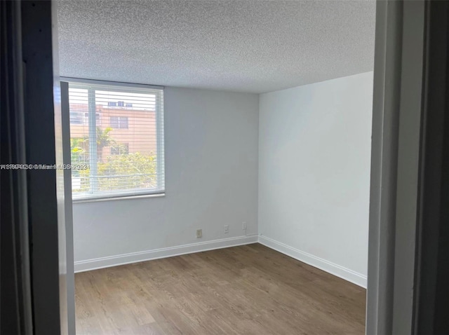 empty room with hardwood / wood-style floors and a textured ceiling