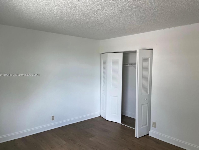 unfurnished bedroom with a textured ceiling, a closet, and dark wood-type flooring