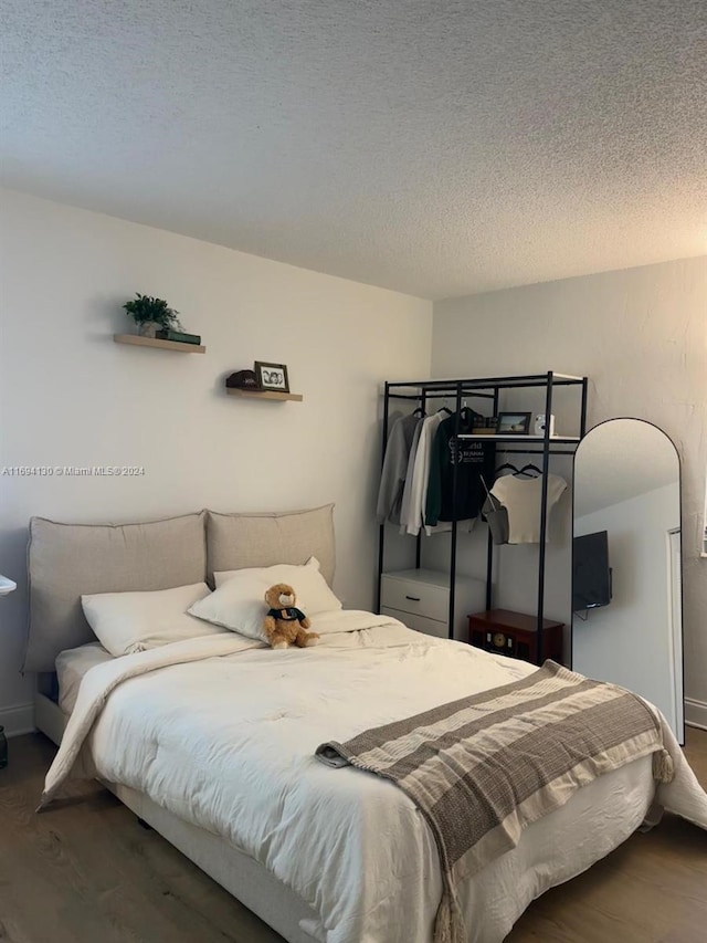 bedroom with hardwood / wood-style floors and a textured ceiling