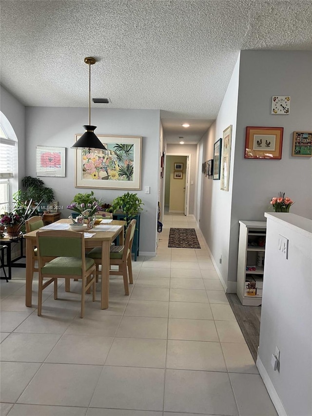 dining space featuring light tile patterned flooring and a textured ceiling