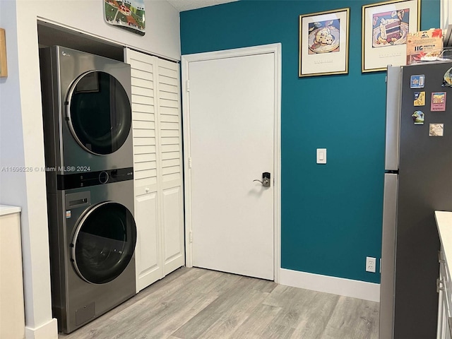 laundry room with stacked washing maching and dryer and light hardwood / wood-style floors