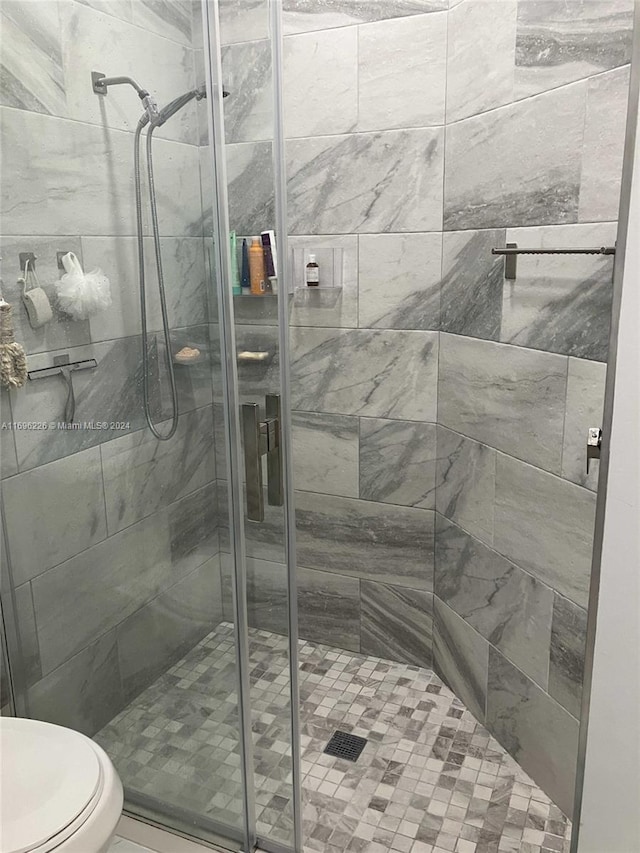 bathroom with a shower with door and toilet