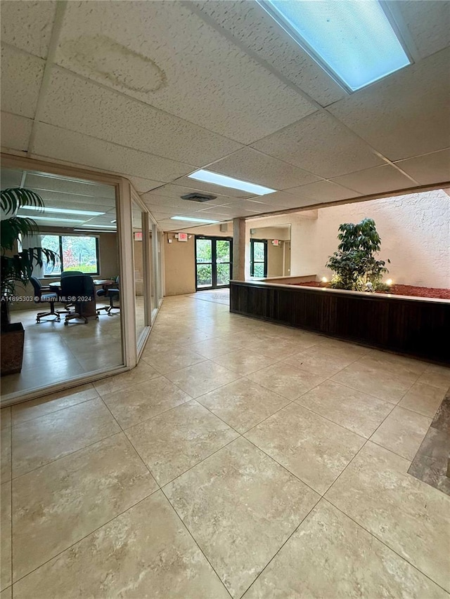 interior space with a drop ceiling and light tile patterned floors