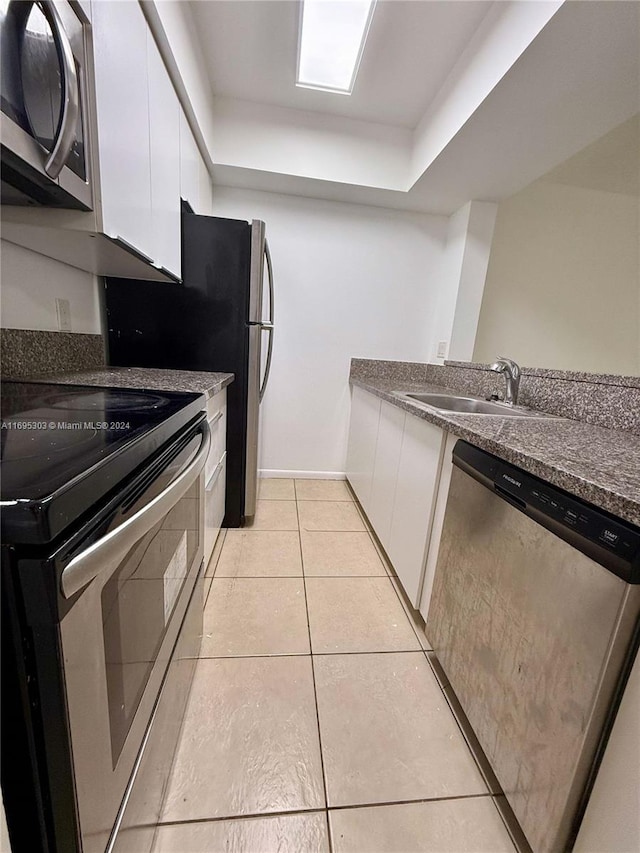 kitchen with light tile patterned floors, stainless steel appliances, white cabinetry, and sink