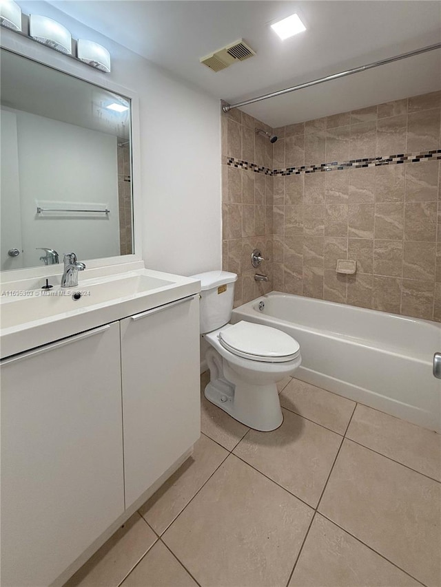 full bathroom with tile patterned flooring, vanity, tiled shower / bath combo, and toilet