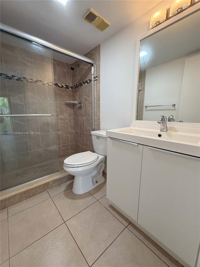 bathroom with tile patterned flooring, vanity, toilet, and a shower with door