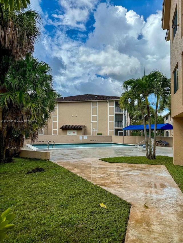 view of pool featuring a lawn and a patio