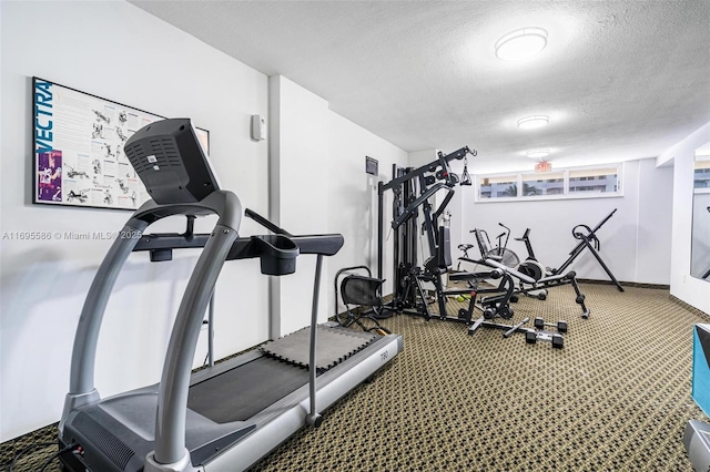 exercise room with carpet floors and a textured ceiling