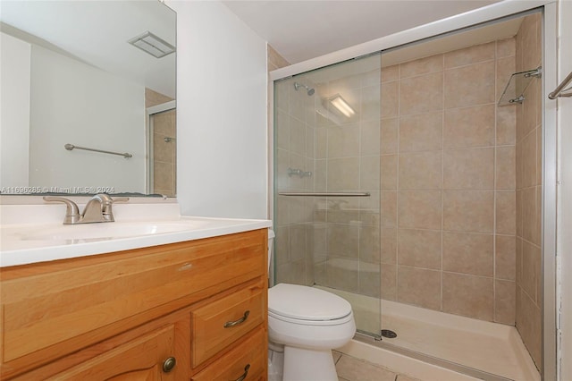 bathroom with tile patterned floors, a shower with door, vanity, and toilet