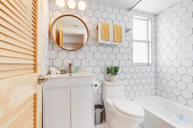 full bathroom featuring tile walls, toilet, vanity, and shower / washtub combination