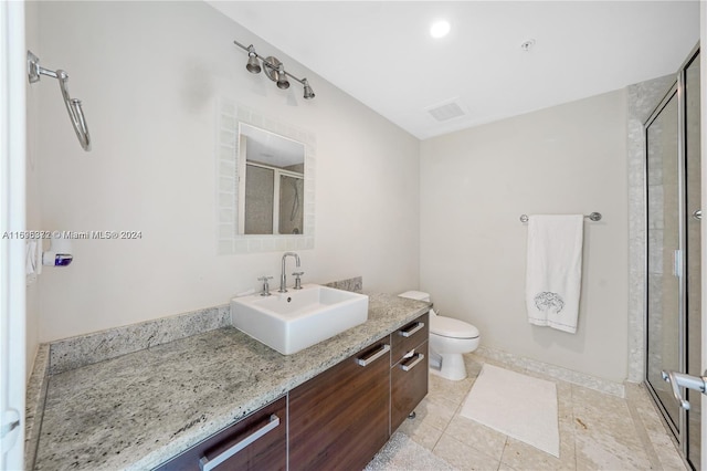 bathroom featuring tile patterned flooring, vanity, toilet, and a shower with shower door