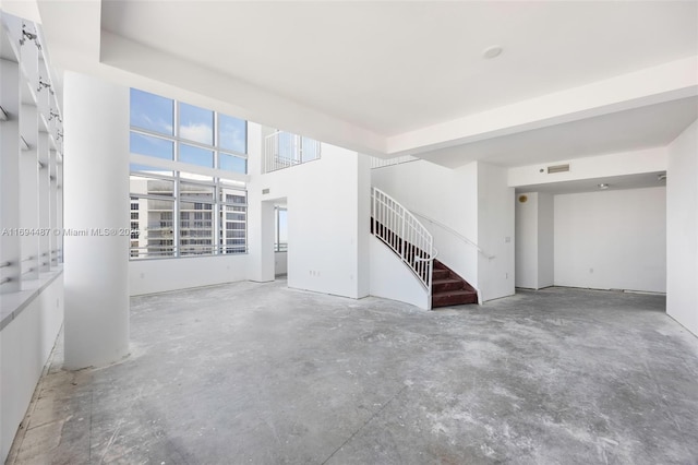 unfurnished living room with visible vents, concrete floors, and stairs