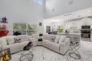 living room featuring a notable chandelier, a towering ceiling, and a wealth of natural light