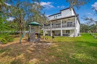 rear view of property featuring a playground and a lawn